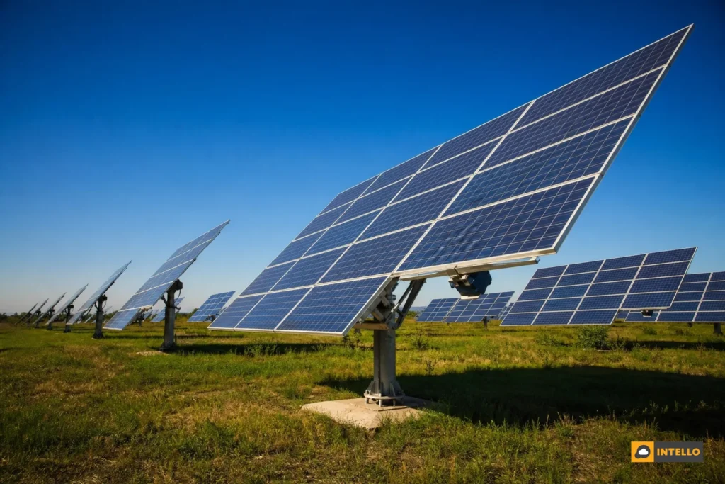 Ground-mounted solar tracking array tilted toward the sun on an Indian commercial site. Photorealistic wide-angle photo of a row of large ground-mounted single-axis solar tracking panels tilted at an angle, following the afternoon sun, set